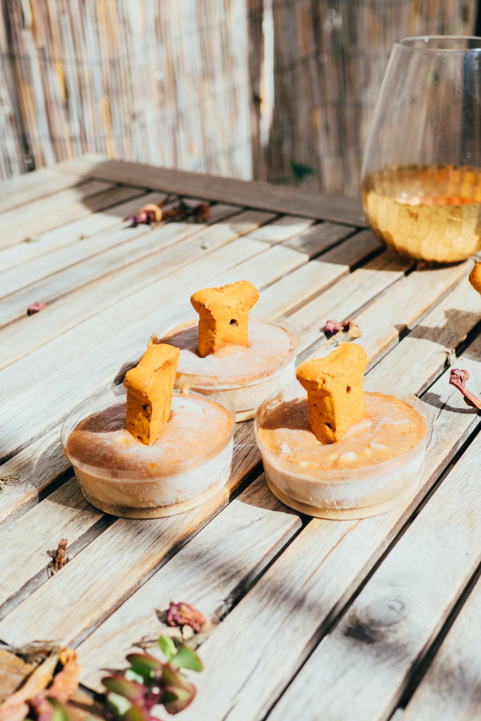 Bone-shaped biscuits in dessert cups on a wooden table.