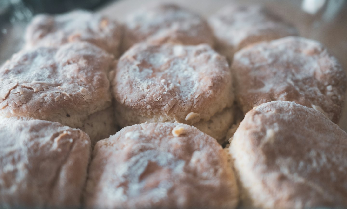 Unbaked biscuits dusted with flour in a baking pan.