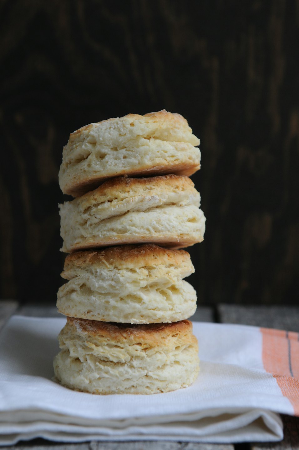 Five golden-brown biscuits stacked on a napkin.